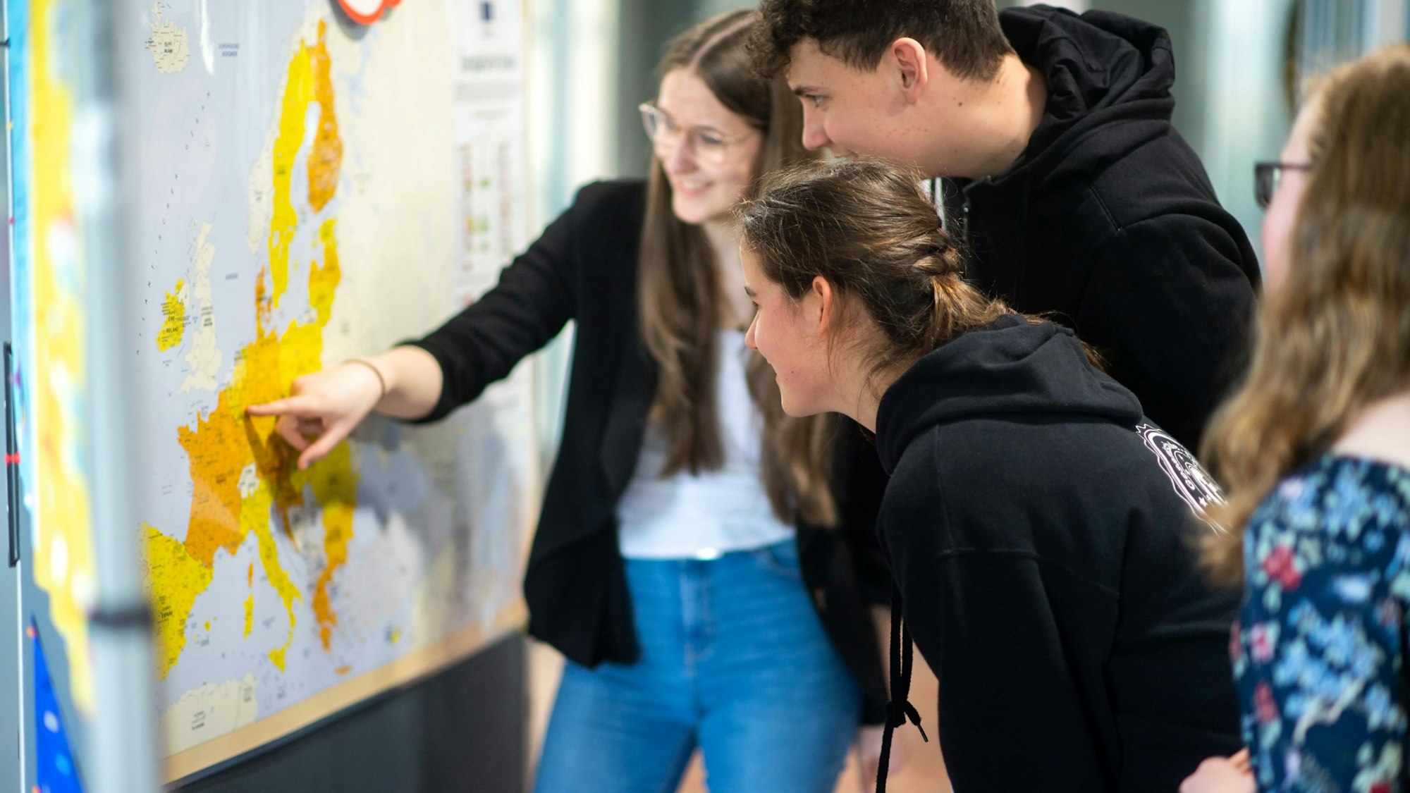 Schüler der Gesamtschule Eifel stehen im Kreishaus vor einer Stellwand der Sonderausstellung zur EU und blicken auf eine Landkarte.