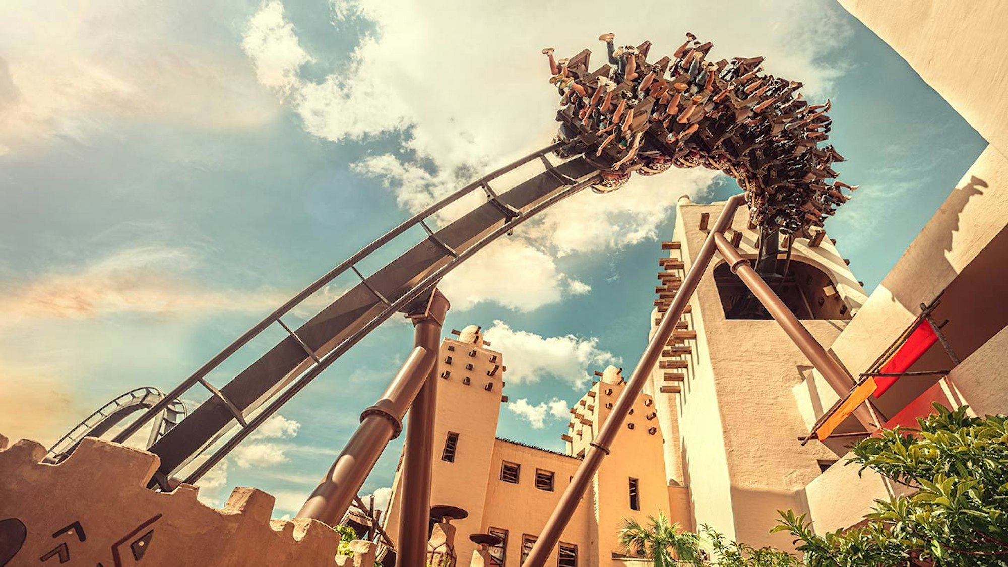 Menschen in einer Achterbahn vor blauem Himmel.