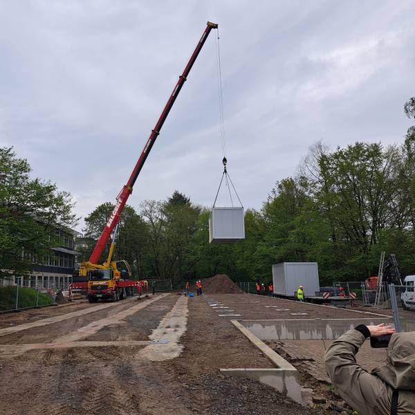 Ein Kran hebt einen Container hoch, der als Ausweichquartier für die Hermann-Voss-Realschule fungieren soll.