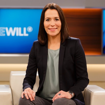 Anne Will sitzt im Studio auf dem Sofa