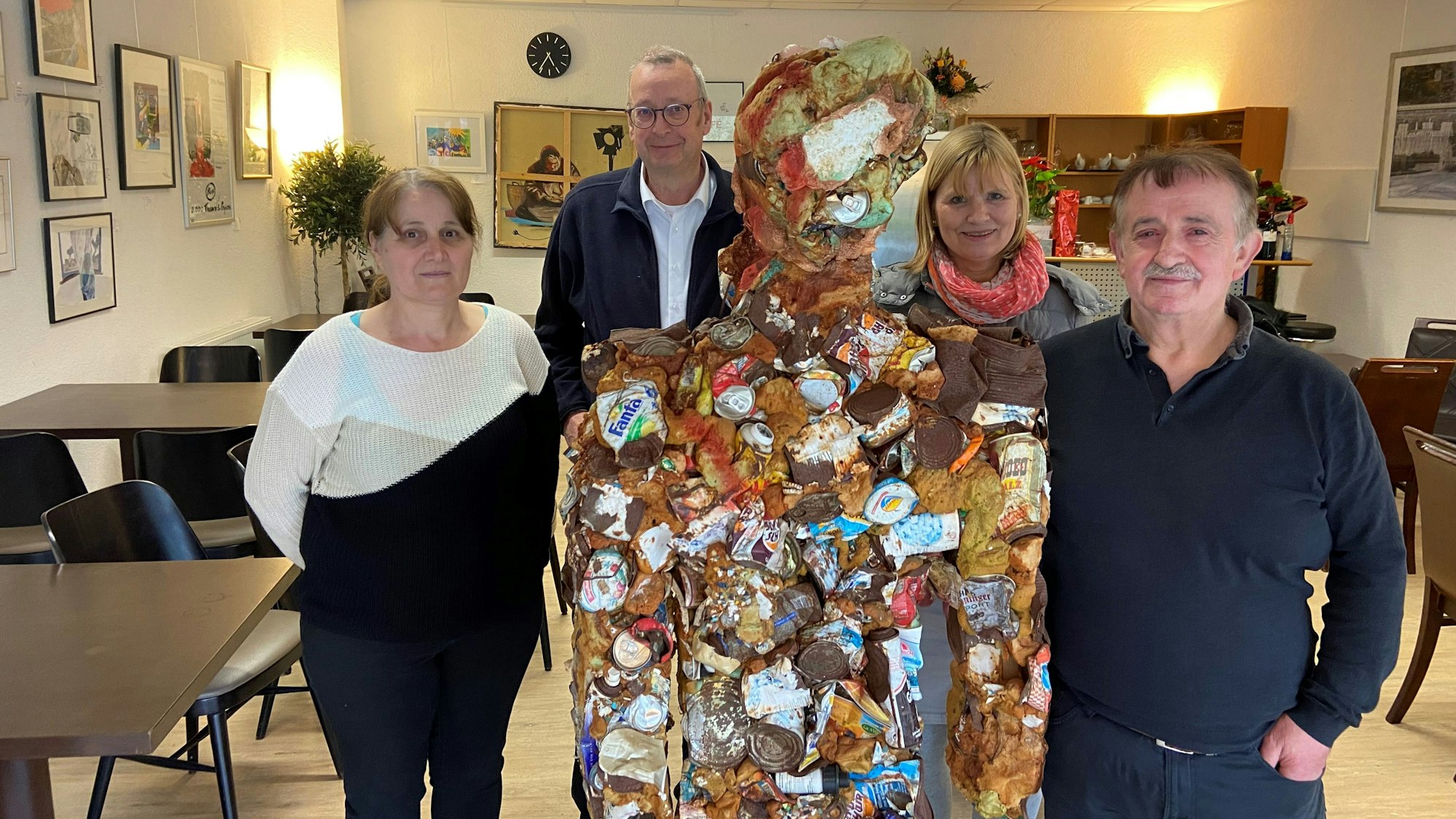 Maria Sanozidis, Dirk Kästel, Jutta Gumprich-Kästel und Anthimos Sanozidis lächeln in die Kamera mit einer Skulptur in der Mitte.