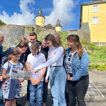 Zu sehen ist eine Familie beim Geocaching vor dem Schloss Homburg.