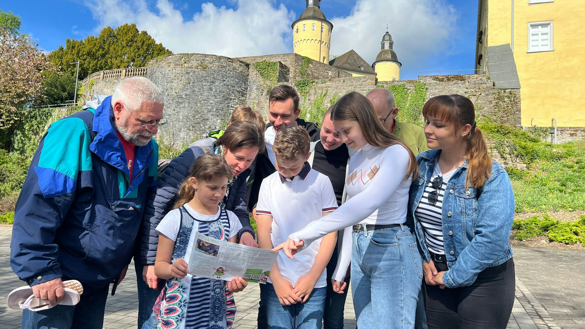 Zu sehen ist eine Familie beim Geocaching vor dem Schloss Homburg.