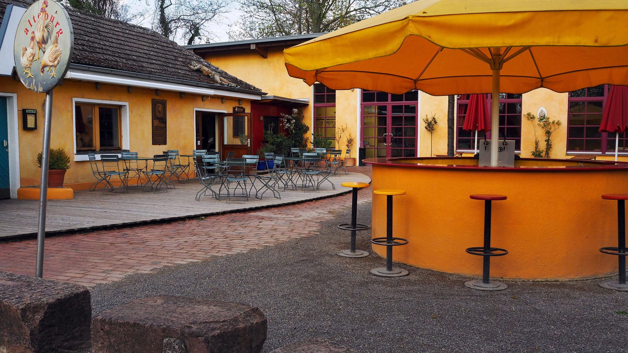 Der Biergarten der Alteburg mit Tischen und Stühlen.