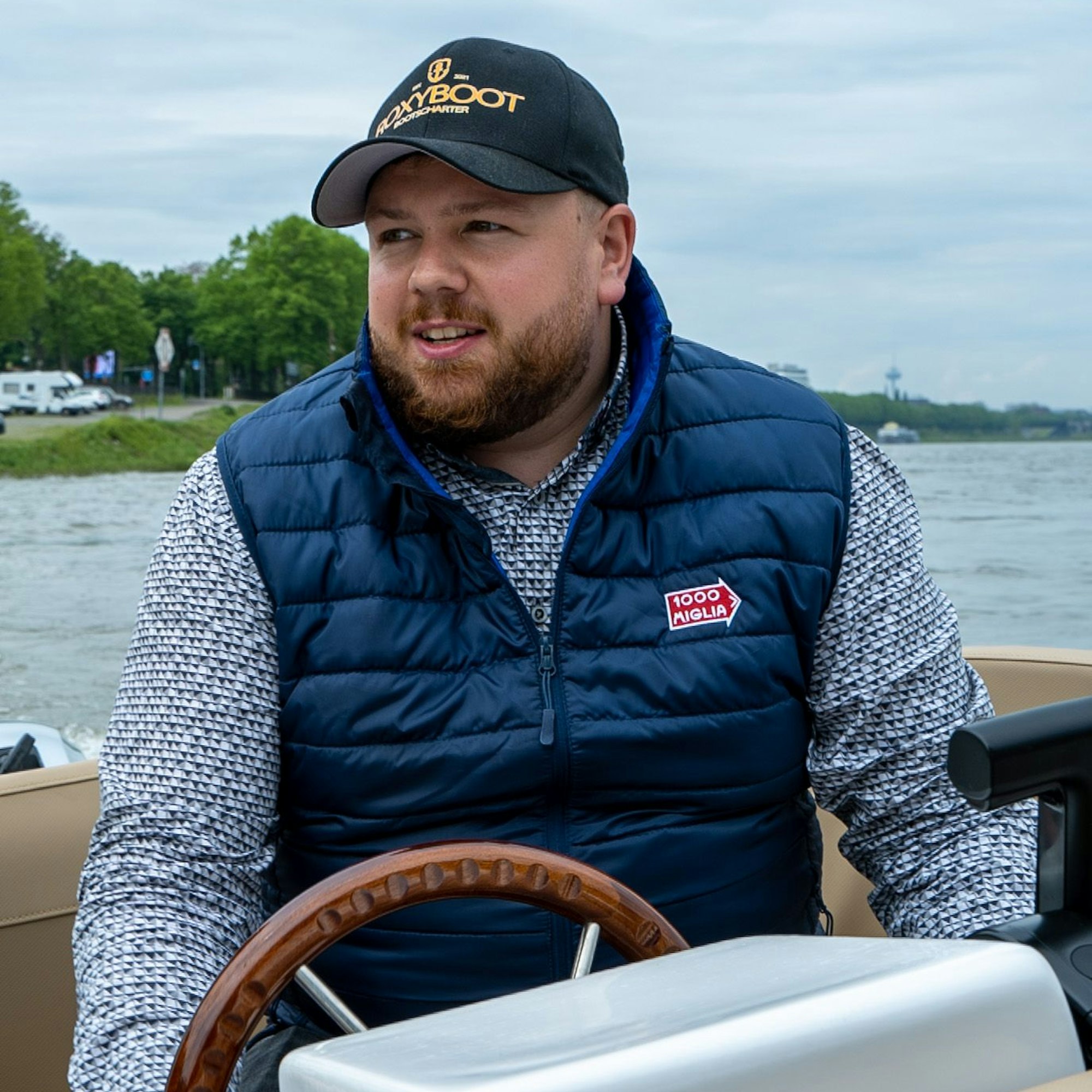 Nico Engels von Roxyboot auf einem Boot. Er trägt eine Kappe und steht am Steuer.