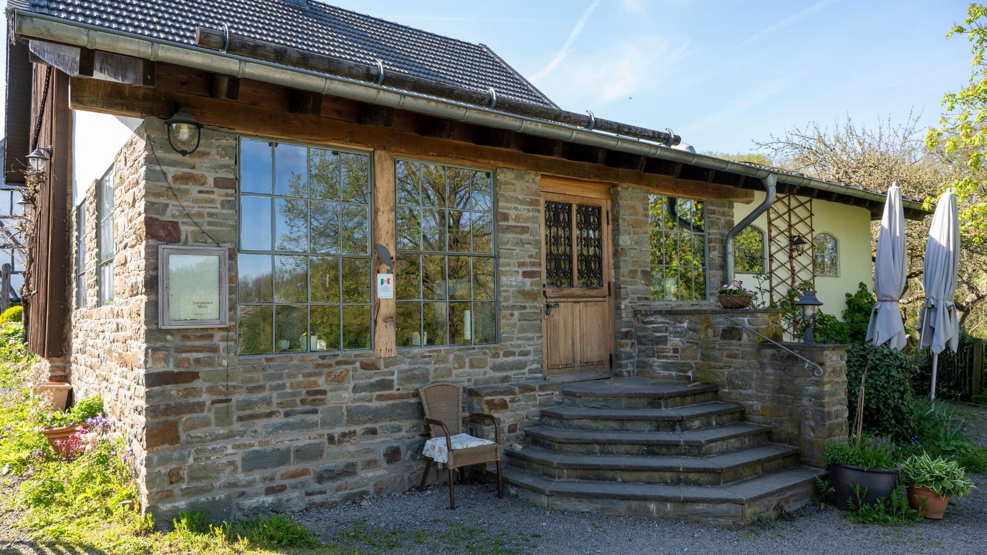 Außenansicht eines Hauses mit Steinfassade und einer Treppe, die zu einer Eingangstür aus Holz führt