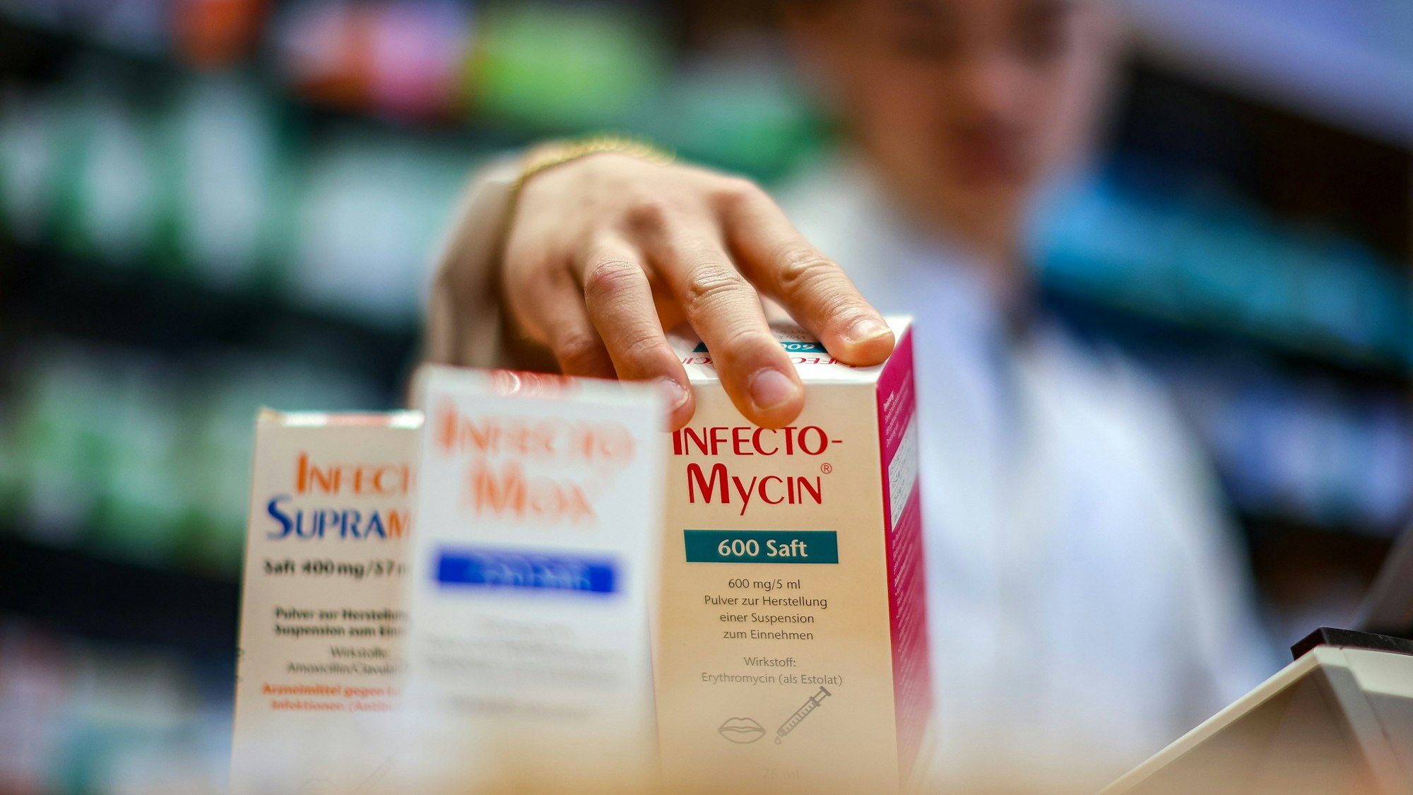 Ein Apotheker greift nach Medikamentenpackungen.