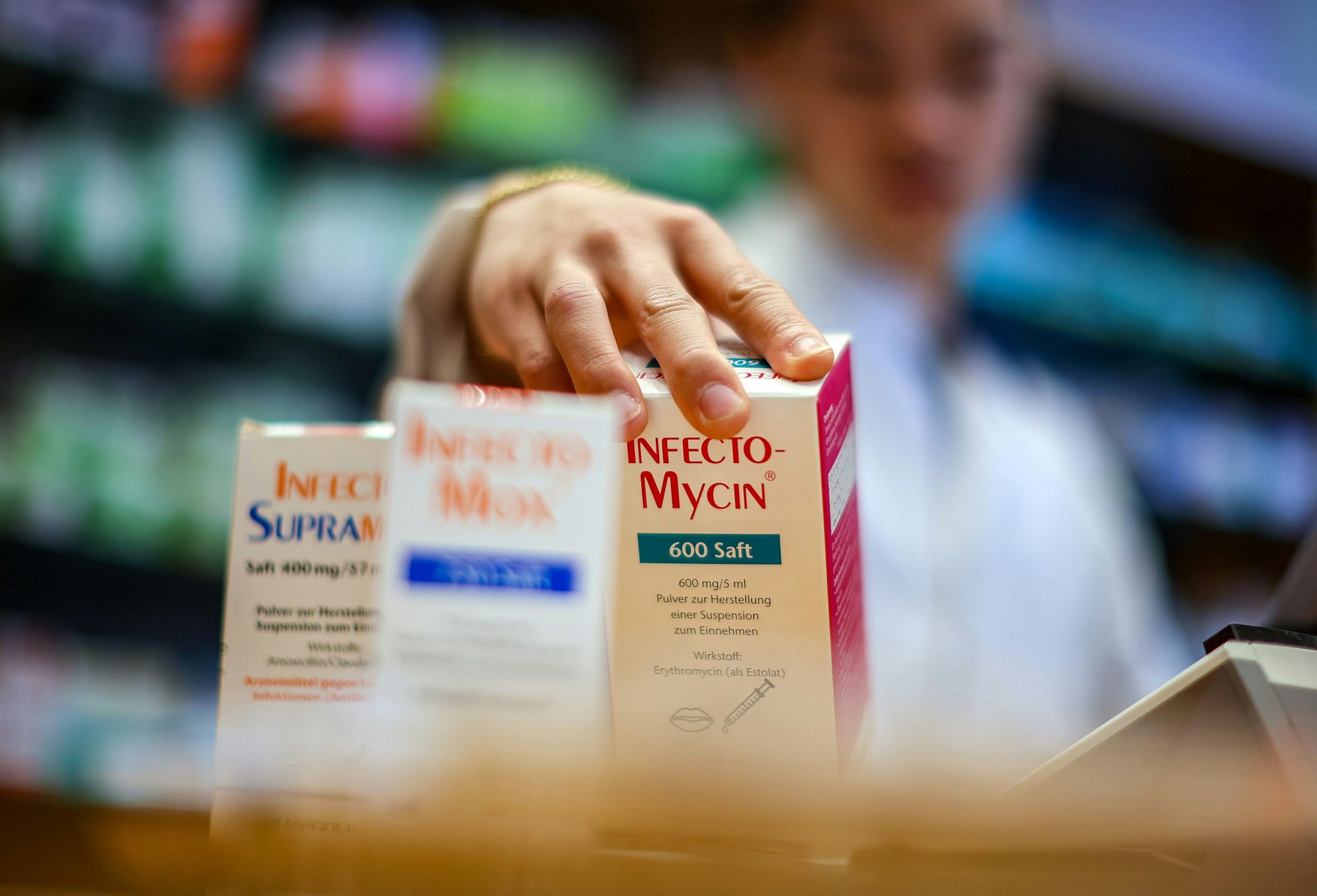 Ein Mitarbeiter einer Apotheke greift nach einer Packung Antibiotikasaft für Kinder.