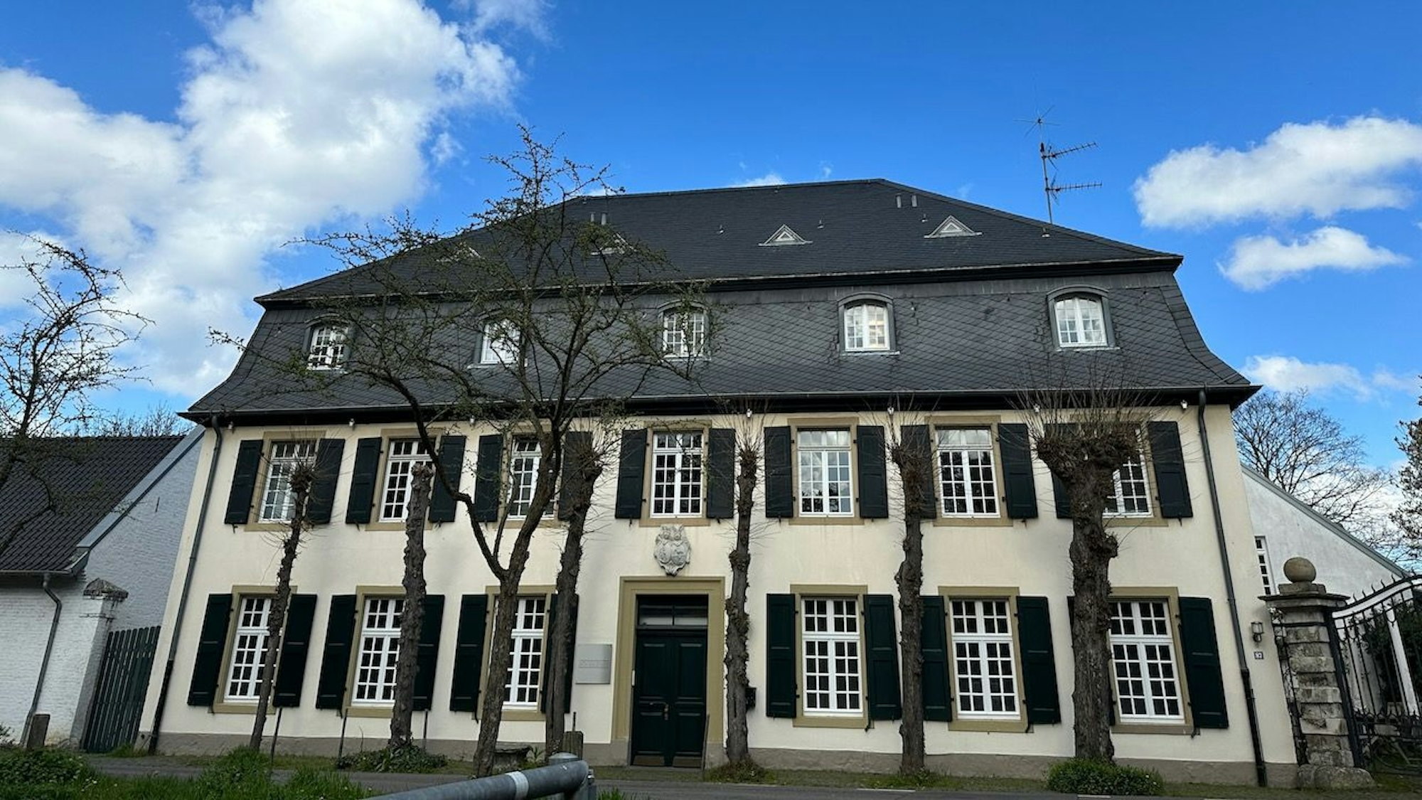 Ein großes Haus mit vielen Sprossenfenstern und Fensterläden ist zu sehen.