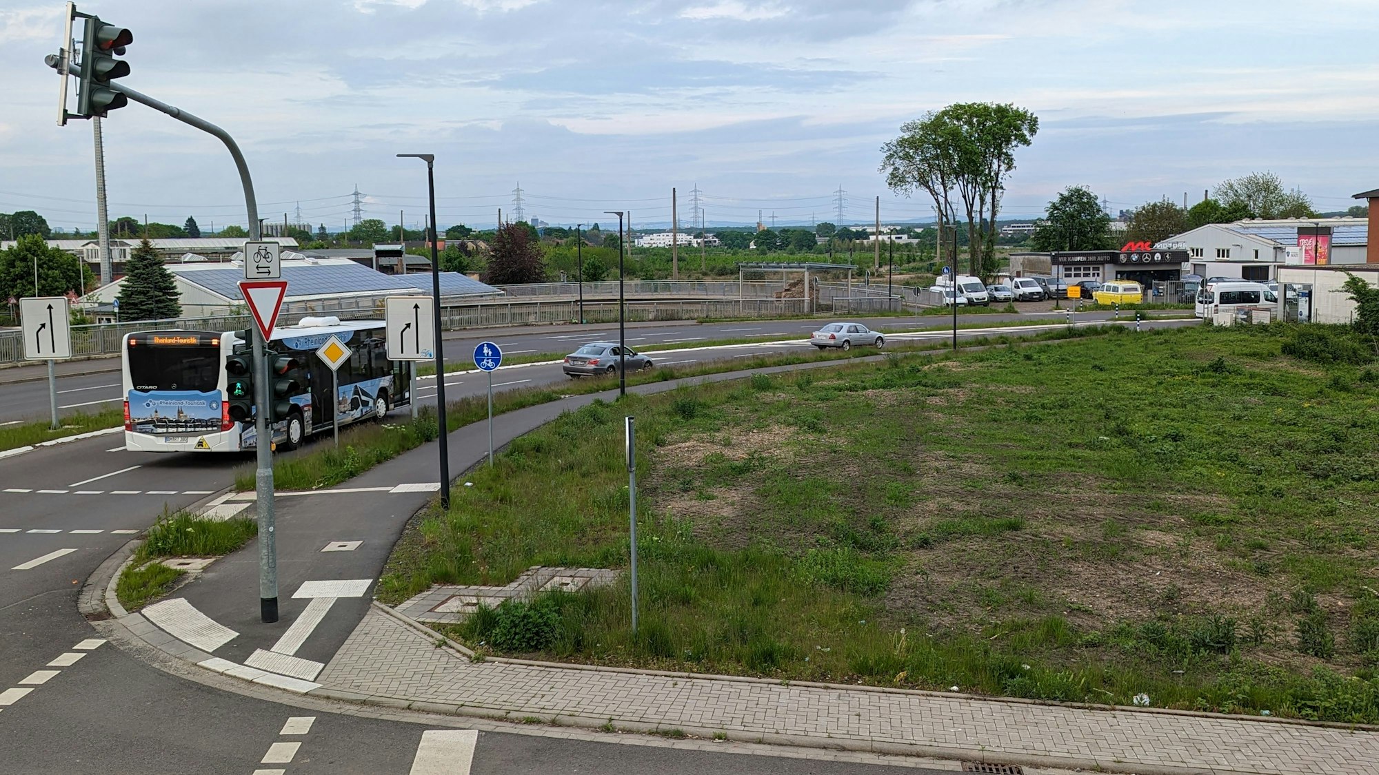 Ein Bus fährt über eine Straße an einer grünen Brachfläche vorbei.