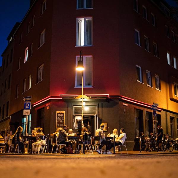 Menschen sitzen vor der Bar „Im Schnörres“.