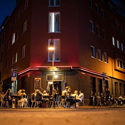 Menschen sitzen vor der Bar „Im Schnörres“.