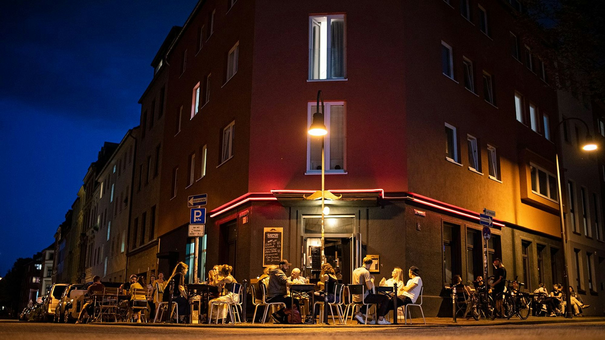 Menschen sitzen vor der Bar „Im Schnörres“.