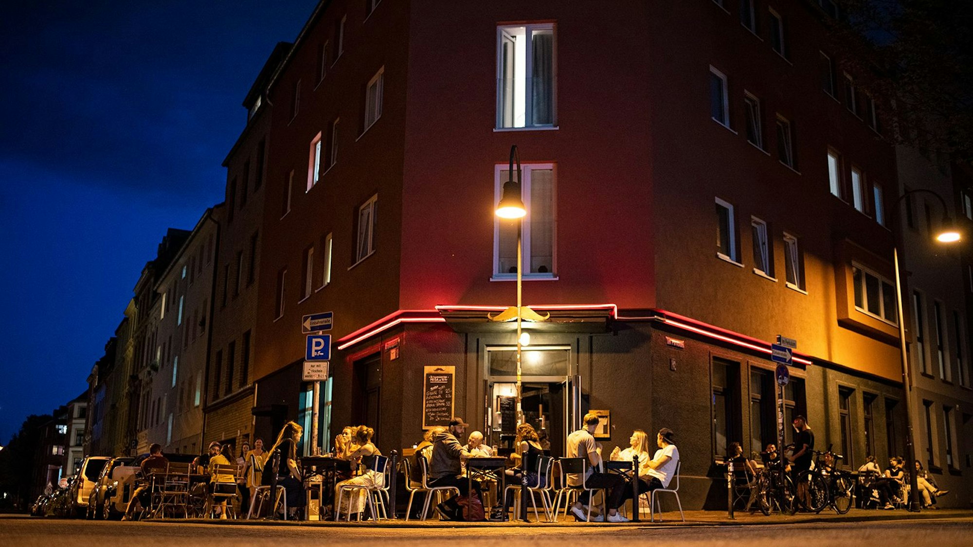 Menschen sitzen vor der Bar „Im Schnörres“.