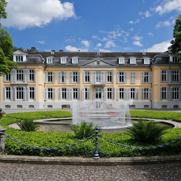 gelbes Schloss mit Park und Springbrunnen im Vordergrund