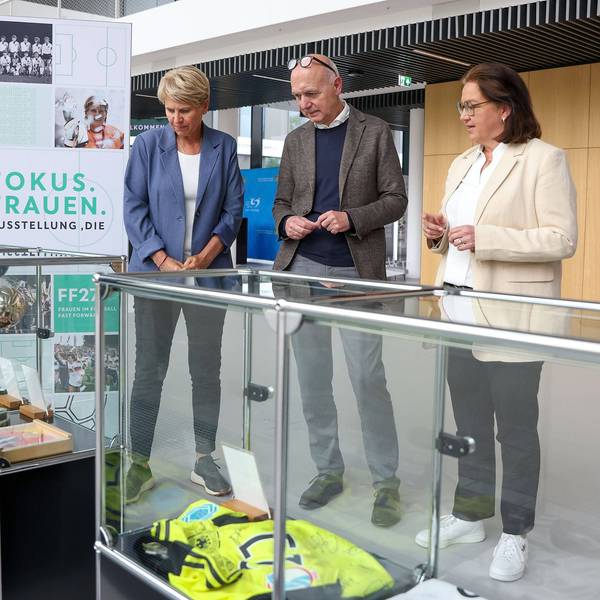 Doris Fitschen, Gesamtkoordinatorin Strategie FIFA Frauen-WM 2027, DFB-Präsident Bernd Neuendorf und DFB-Generalsekretärin Heike Ullrich schauen sich die Ausstellung zur Geschichte des Frauenfußballs an.