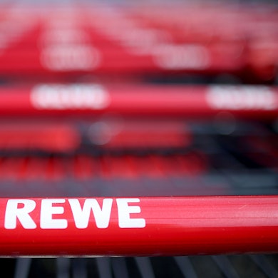 Einkaufswagen stehen vor einem Rewe-Supermarkt in Köln.