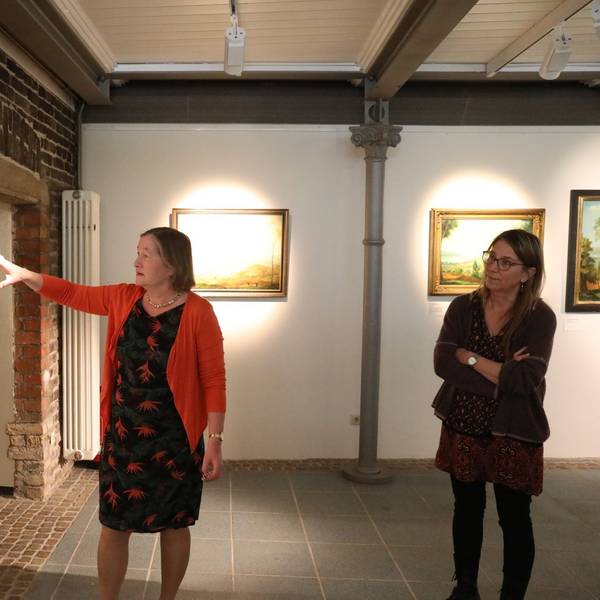 Zwei Frauen begutachten Gemälde in einer Ausstellung.