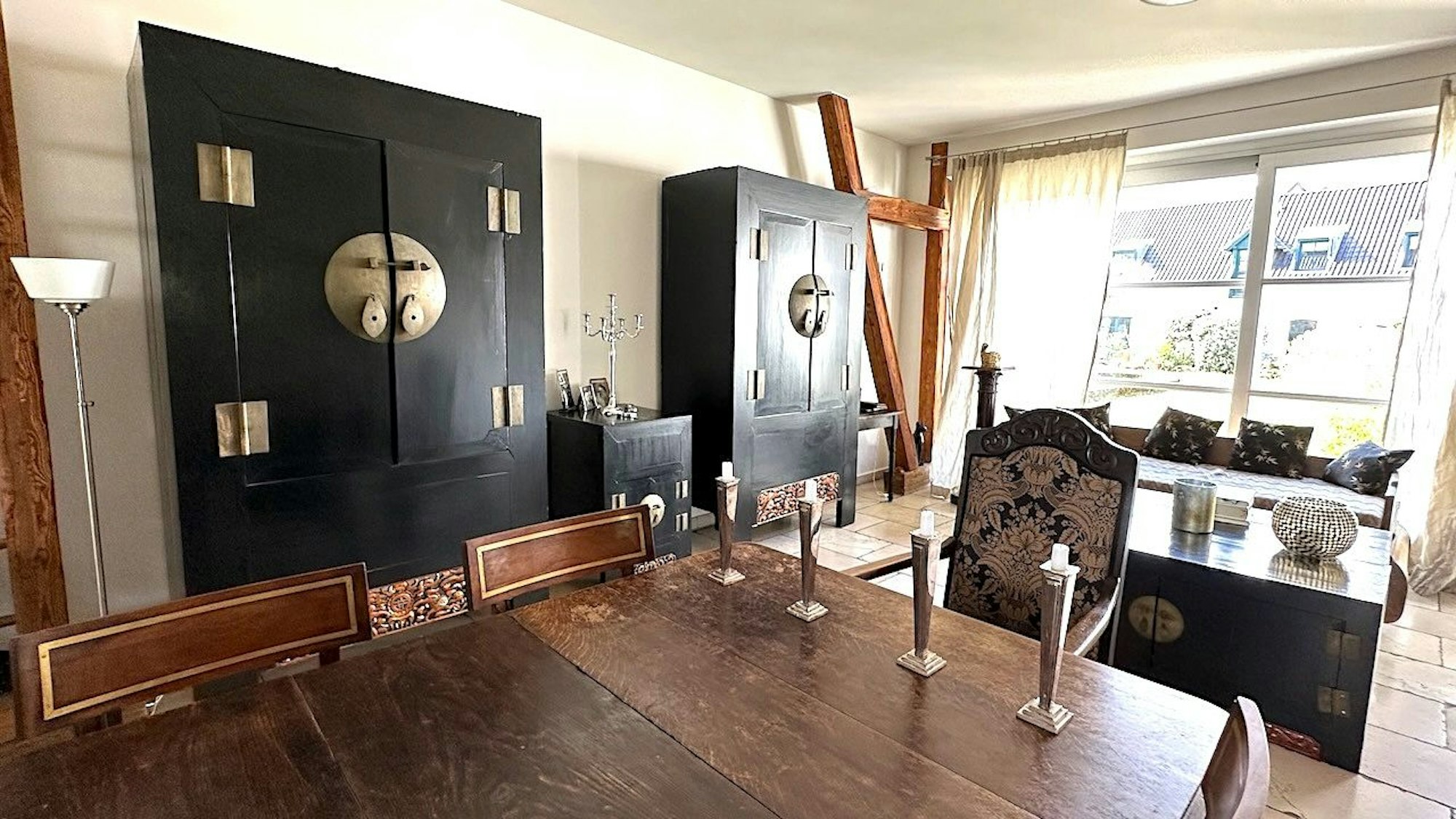 Blick ins Wohnzimmer, wo ein massiver Holztisch und zwei große Schränke im China-Stil stehen