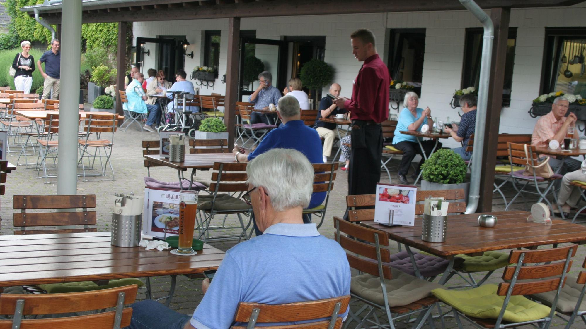 Mehrere Personen sitzen an Tischen und Stühlen.