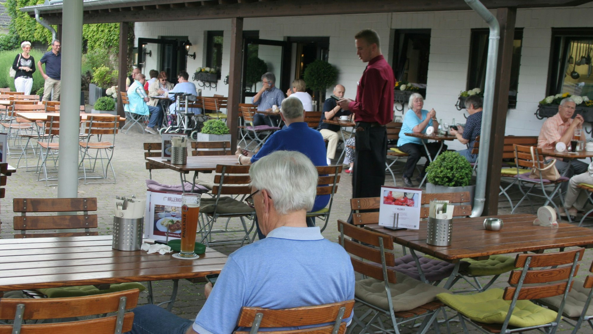 Mehrere Personen sitzen an Tischen und Stühlen.
