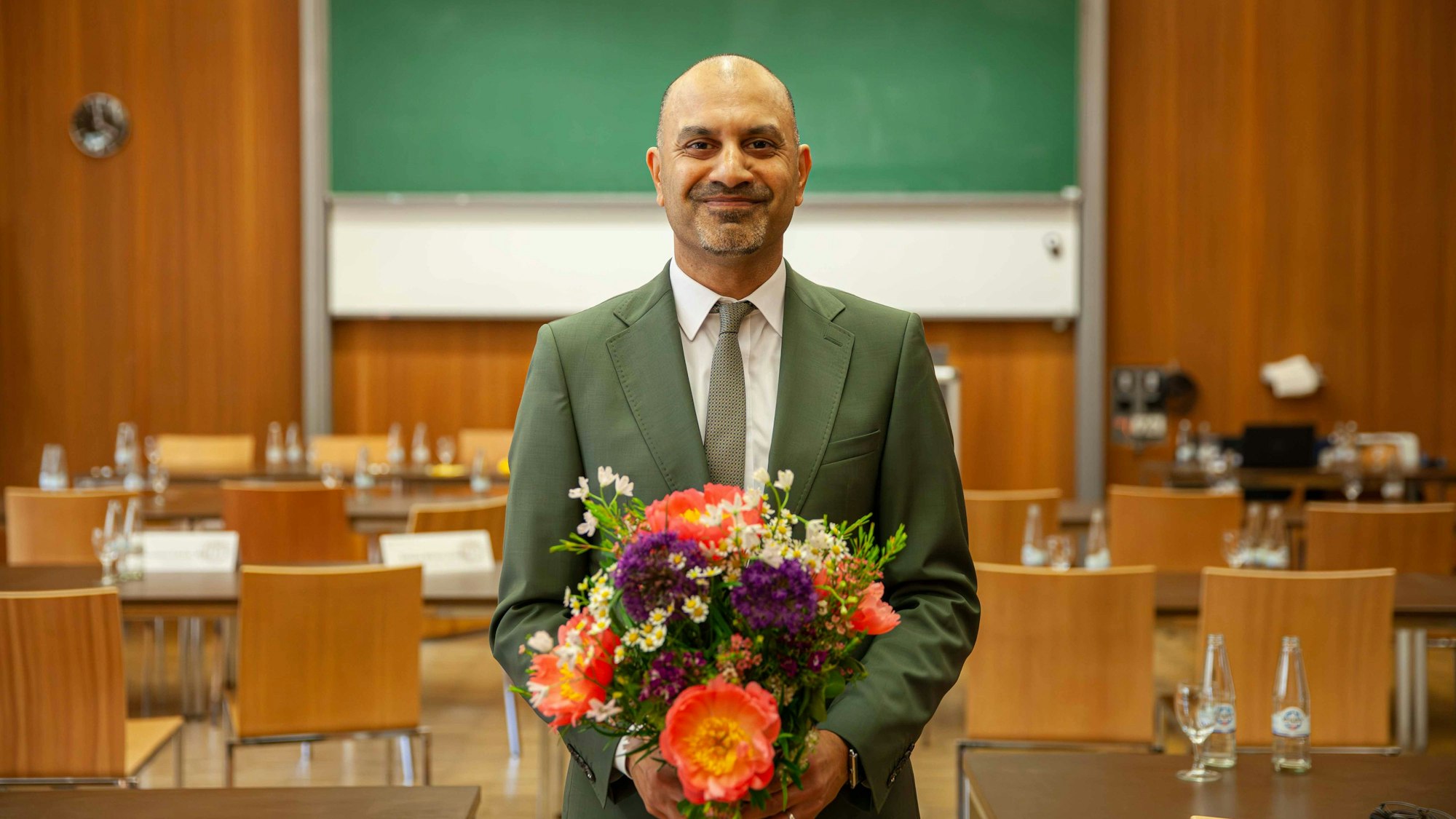 Professor Joybrato Mukherjee lacht in die Kamera und hält einen Blumenstrauß in den Händen.
