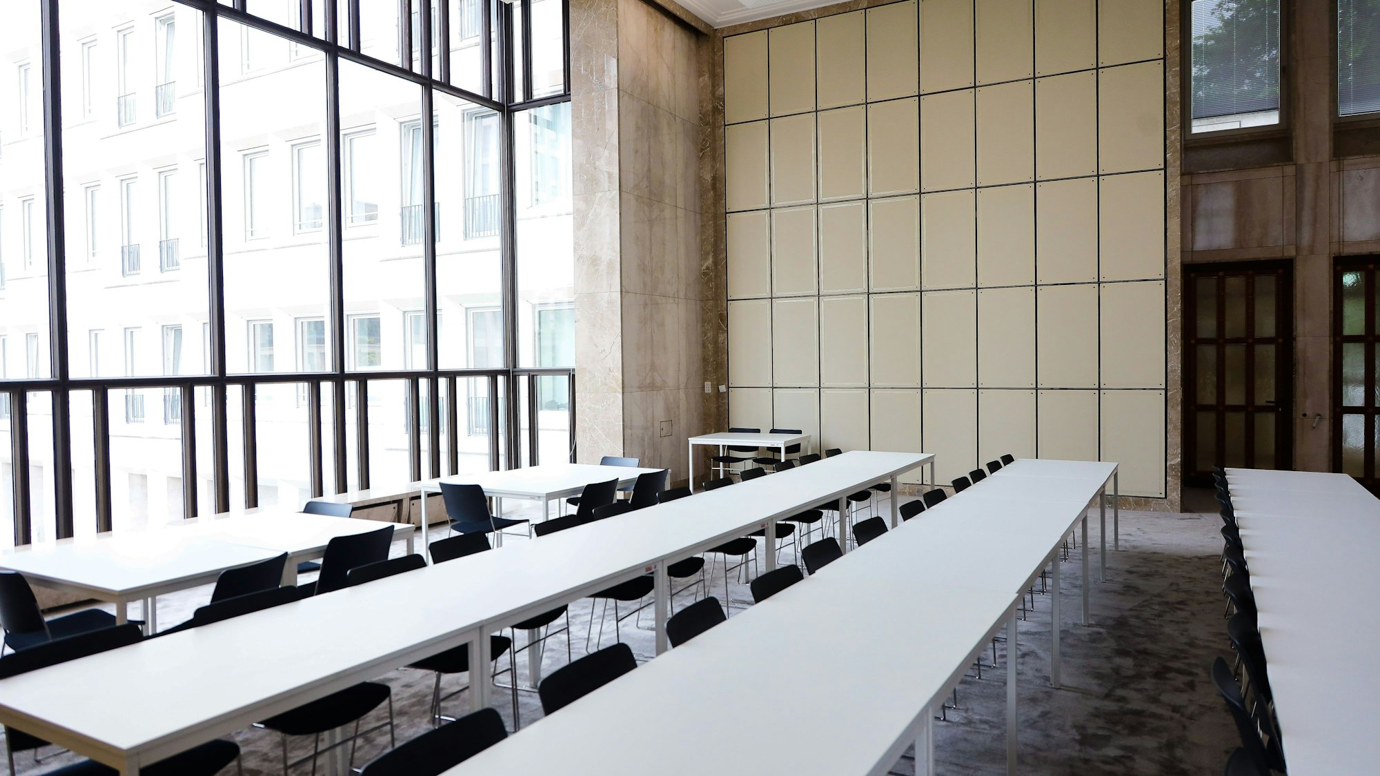 Innenraum mit Tisch- und Stuhlreihen.