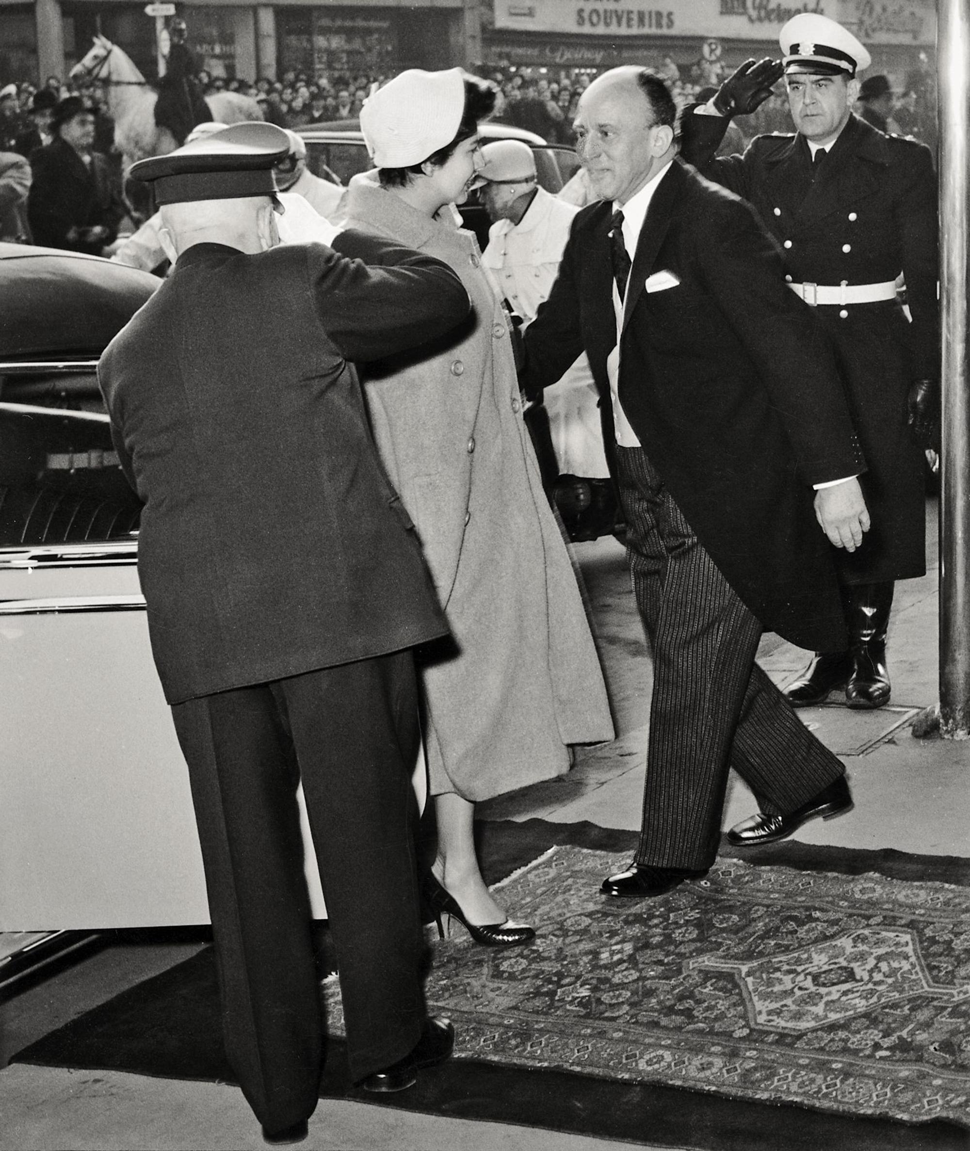 Kaiserin Soraya wird 1955 am Hoteleingang empfangen, im Hintergrund ist eine große Menschenmenge zu sehen.