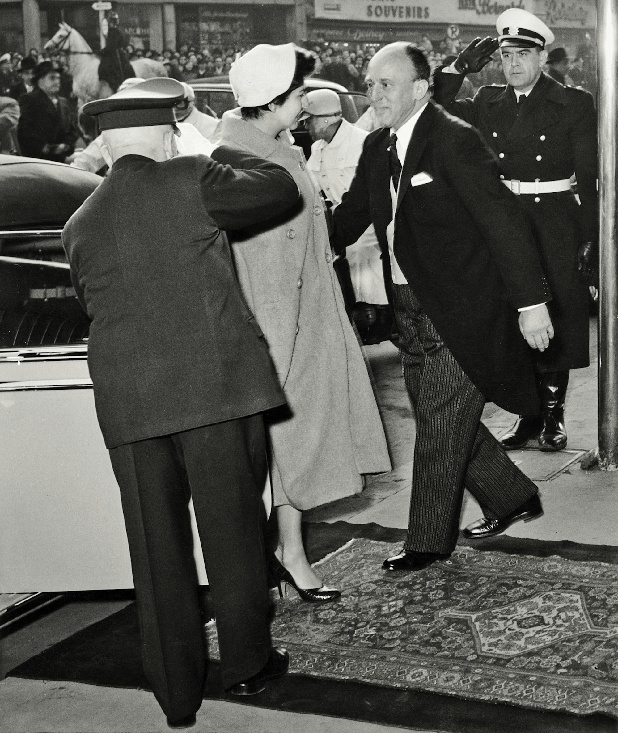 Kaiserin Soraya wird 1955 am Hoteleingang empfangen, im Hintergrund ist eine große Menschenmenge zu sehen.