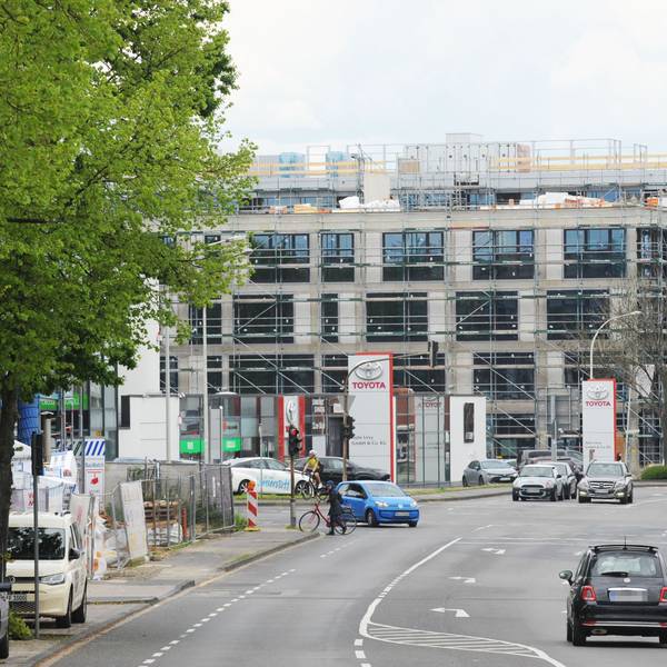 Das neue Neobel Stadtquartier in Frechen ist aktuell noch eine Baustelle. Eine Straße mit fahrenden Autos ist zu sehen, rechts im Bild ist eine Shell-Tankstelle.