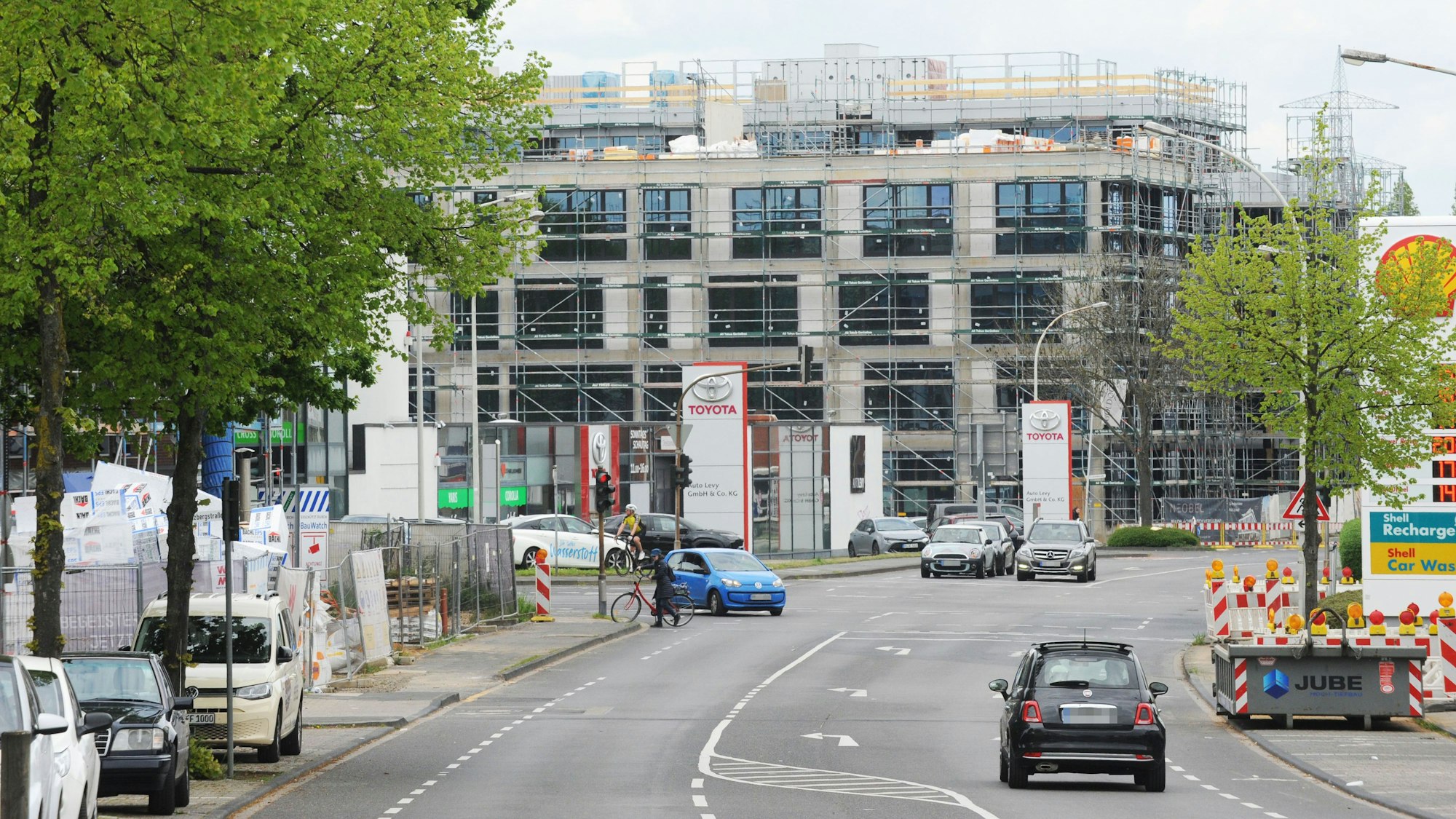 Das neue Neobel Stadtquartier in Frechen ist aktuell noch eine Baustelle. Eine Straße mit fahrenden Autos ist zu sehen, rechts im Bild ist eine Shell-Tankstelle.