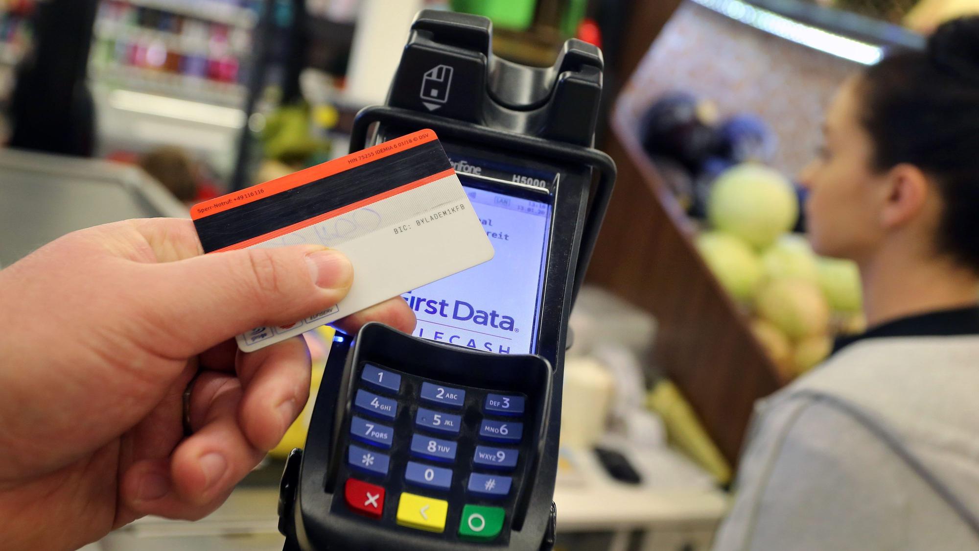 ARCHIV - 13.01.2020, Bayern, Kaufbeuren: ILLUSTRATION - Eine EC-Karte wird an den Bezahl-Terminal an der Kasse eines Supermarktes gehalten. Der Trend zur Karten-Zahlung beim Einkaufen im stationären Handel weiter hält an. (zu dpa «Einzelhandel: Trend zur Kartenzahlung hält an») Foto: Karl-Josef Hildenbrand/dpa +++ dpa-Bildfunk +++