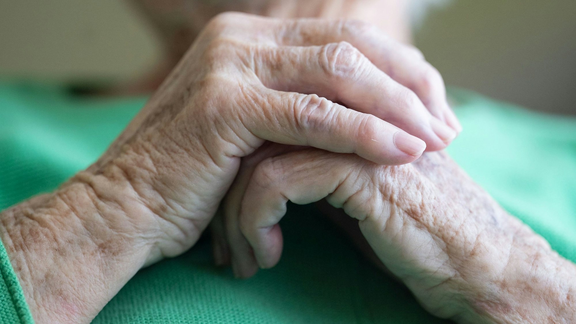 Eine Seniorin faltet ihre Hände.
