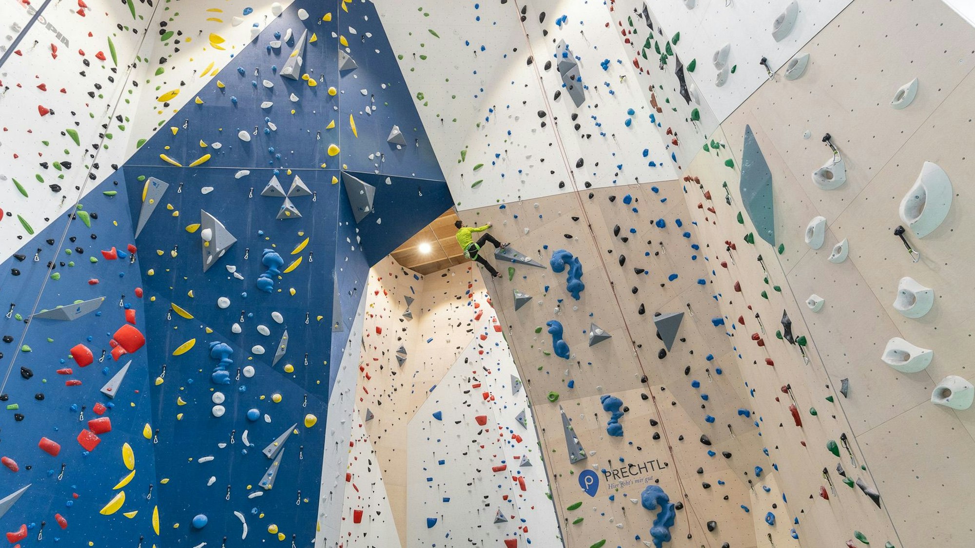 Ein Mensch klettert eine Kletterwand hoch.