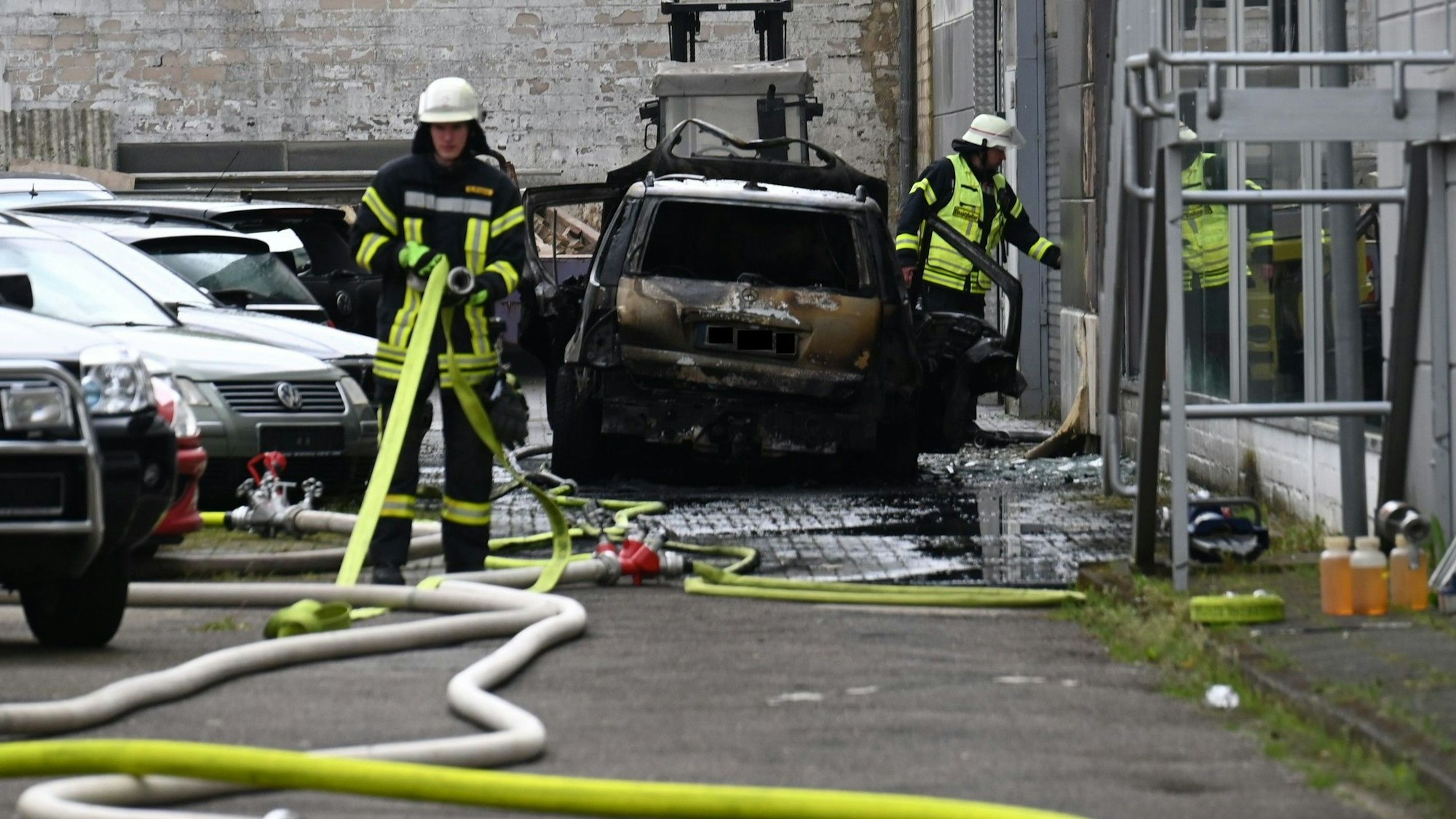 Das Bild Einsatzkräfte der Feuerwehr, die Löschschläuche aufrollen.