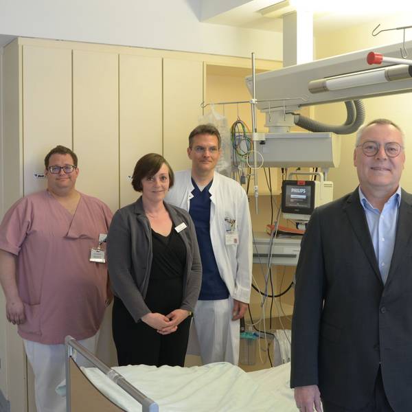 Der Neurologie-Chefarzt Dr. Hartmut Bauer (v.r.) und der leitende Oberarzt Dr. Gaius Masset mit der stellvertretenden Leiterin des Kreisgesundheitsamtes, Sonja Zingsheim, und Pflegefachkraft Marco Günther an einem Behandlungsbett der Stroke Unit.