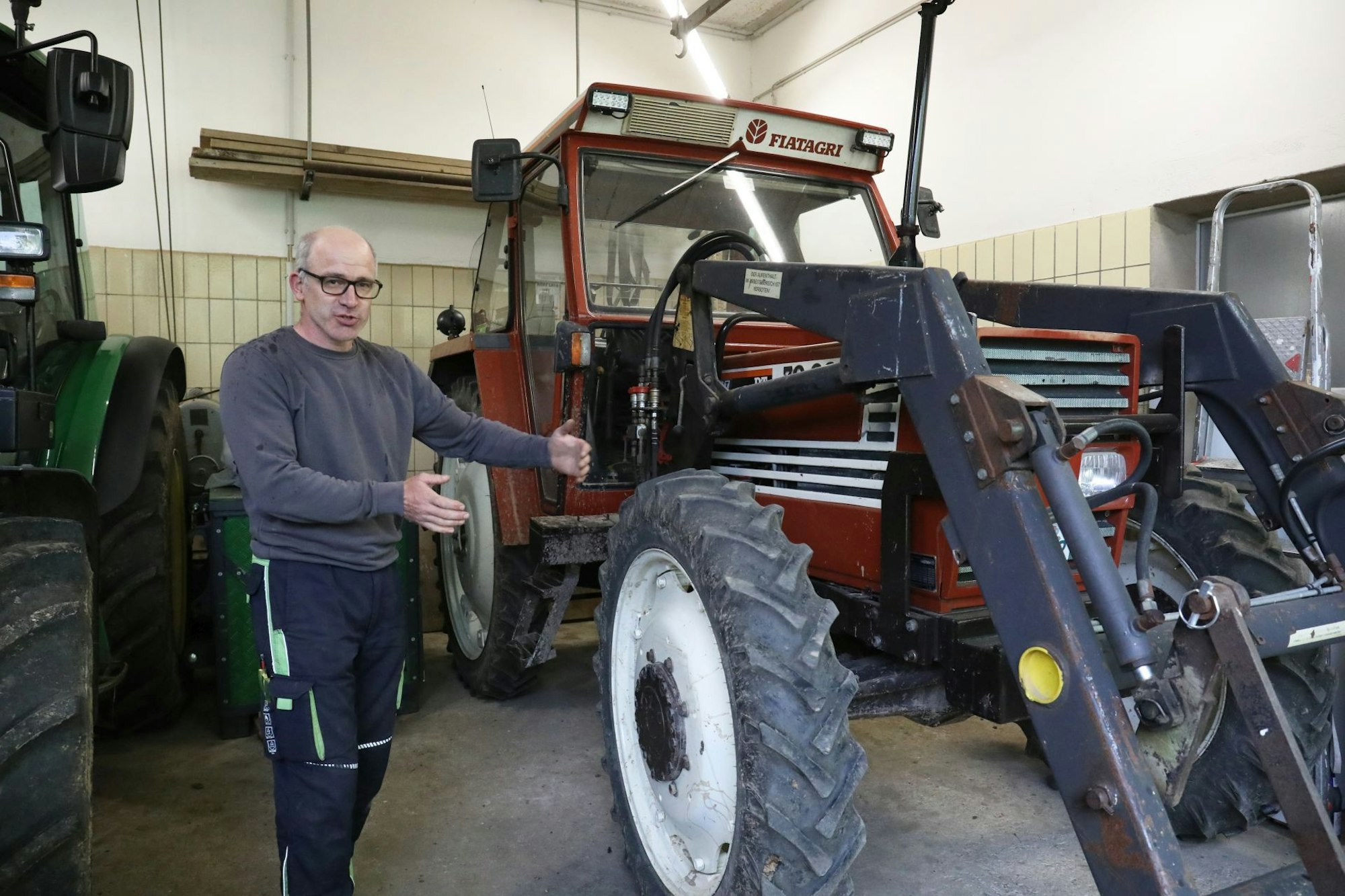 Ein Mann steht neben einem roten Traktor.