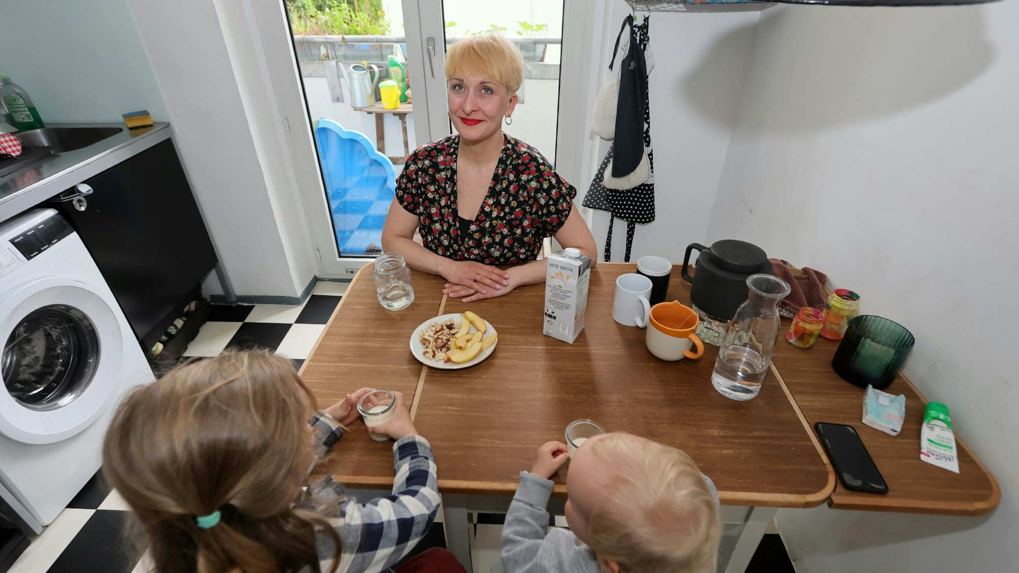 Die Kölnerin Sonja Kunz sitzt mit ihren beiden Kindern am Küchentisch. Sie trinken ein Glas Hafermilch.