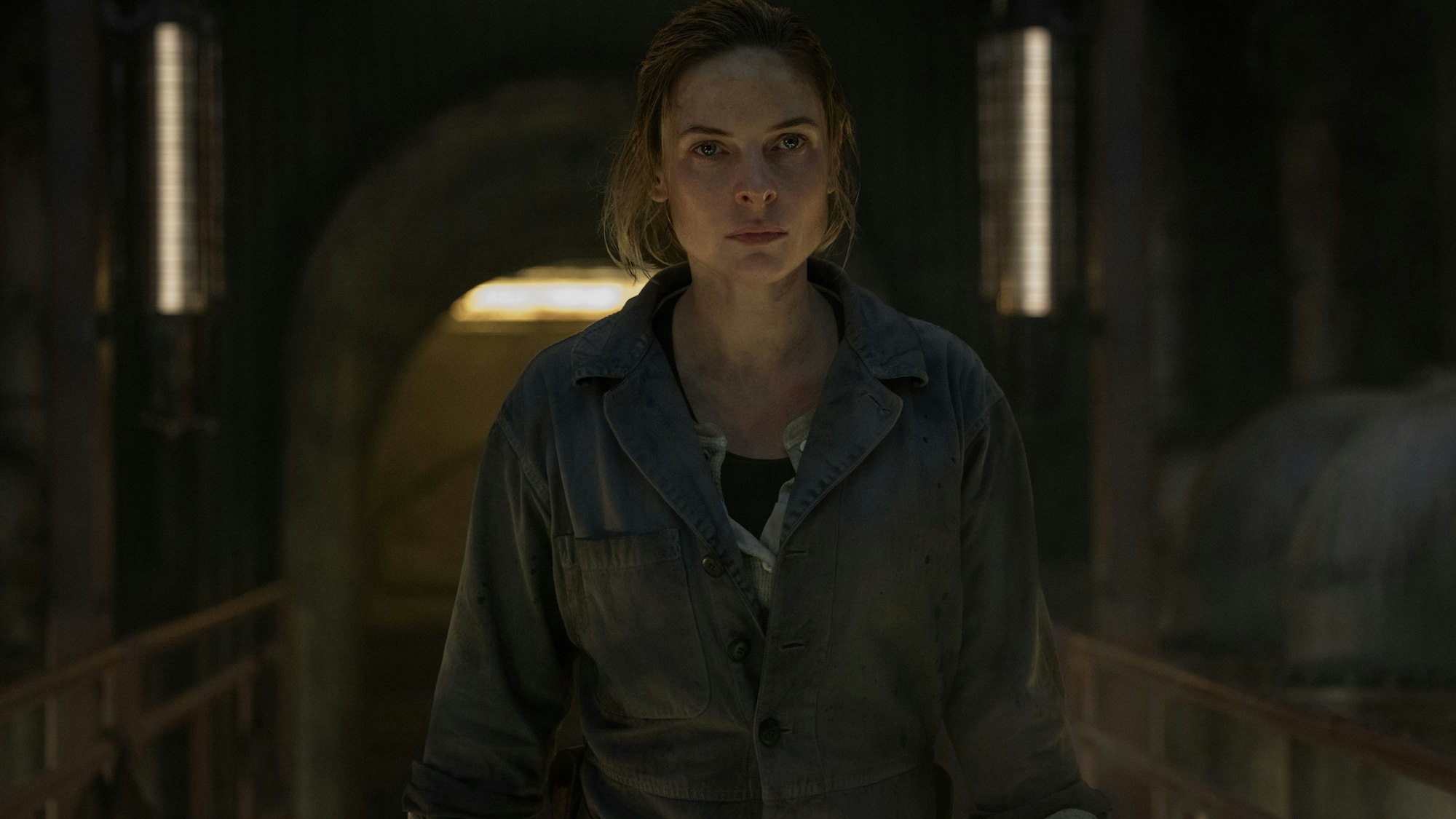 Eine Frau steht in Arbeitskleidung auf einer Stahlbrücke.