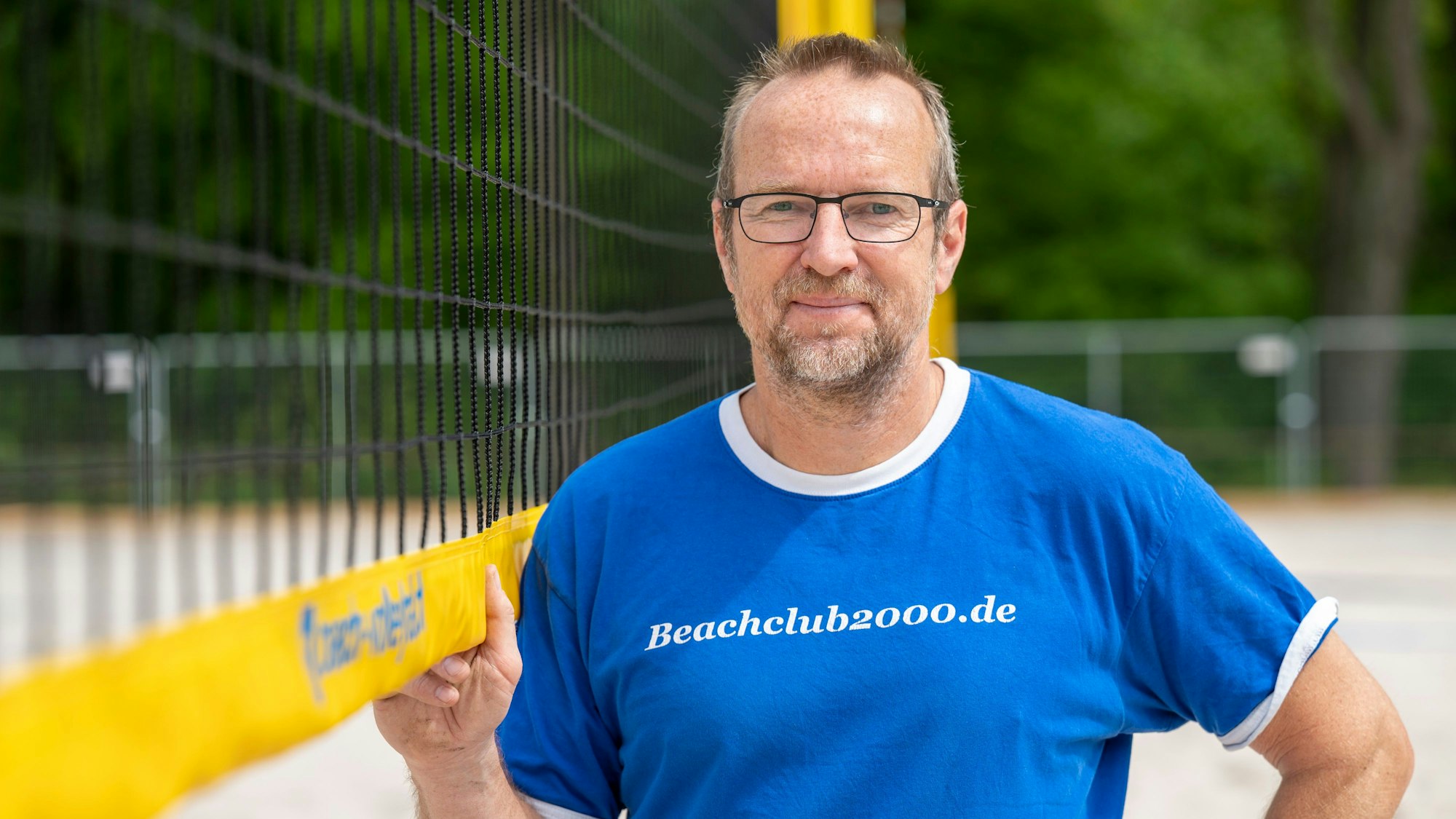 Der Mann steht am Volleyballnetz.