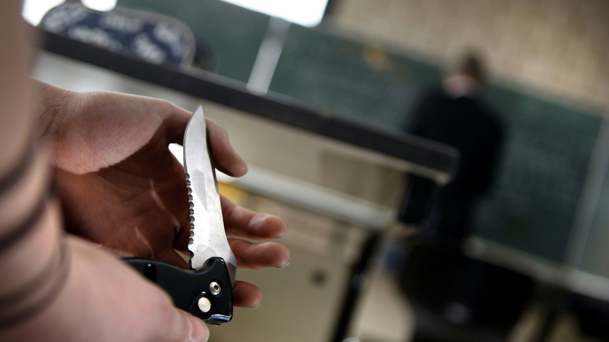 Eine Schülerin zeigt während des Unterrichts einer Mitschülerin ihr Klappmesser.