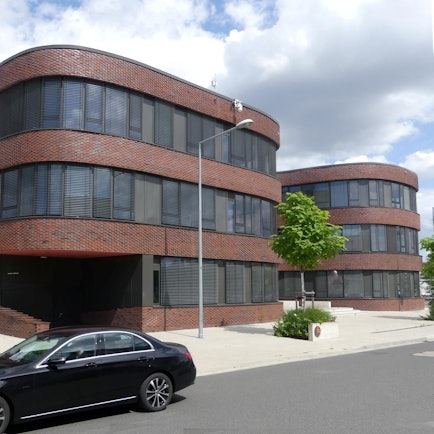 Vor einem Bürogebäude steht ein Auto.