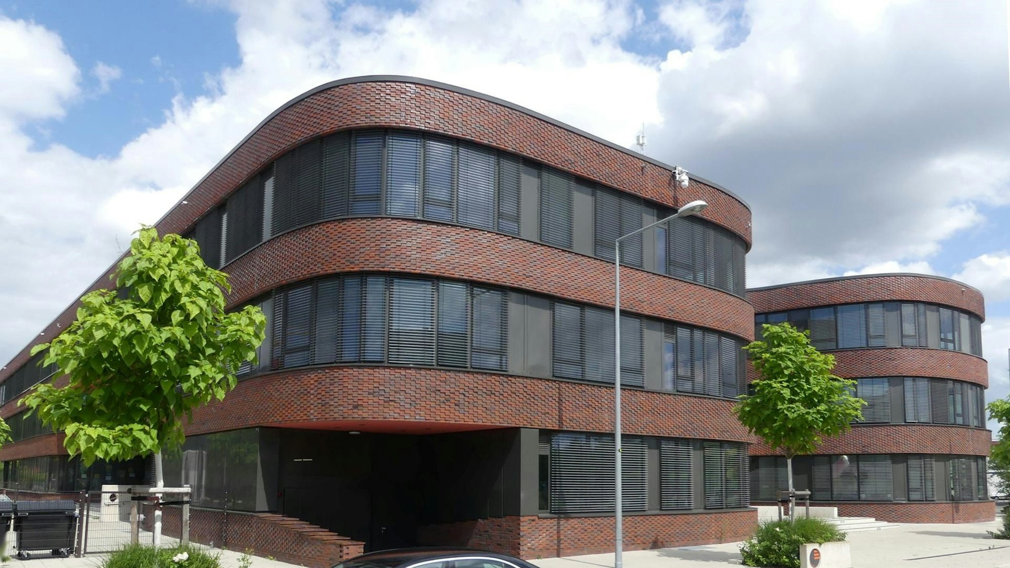 Vor einem Bürogebäude steht ein Auto.