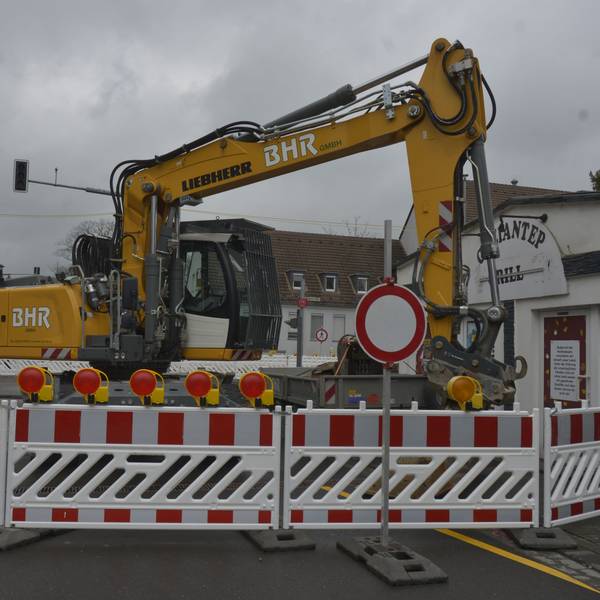 Die Baustelle ist zu sehen. Ein Bagger steht hinter der Absperrung.