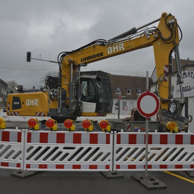 Die Baustelle ist zu sehen. Ein Bagger steht hinter der Absperrung.