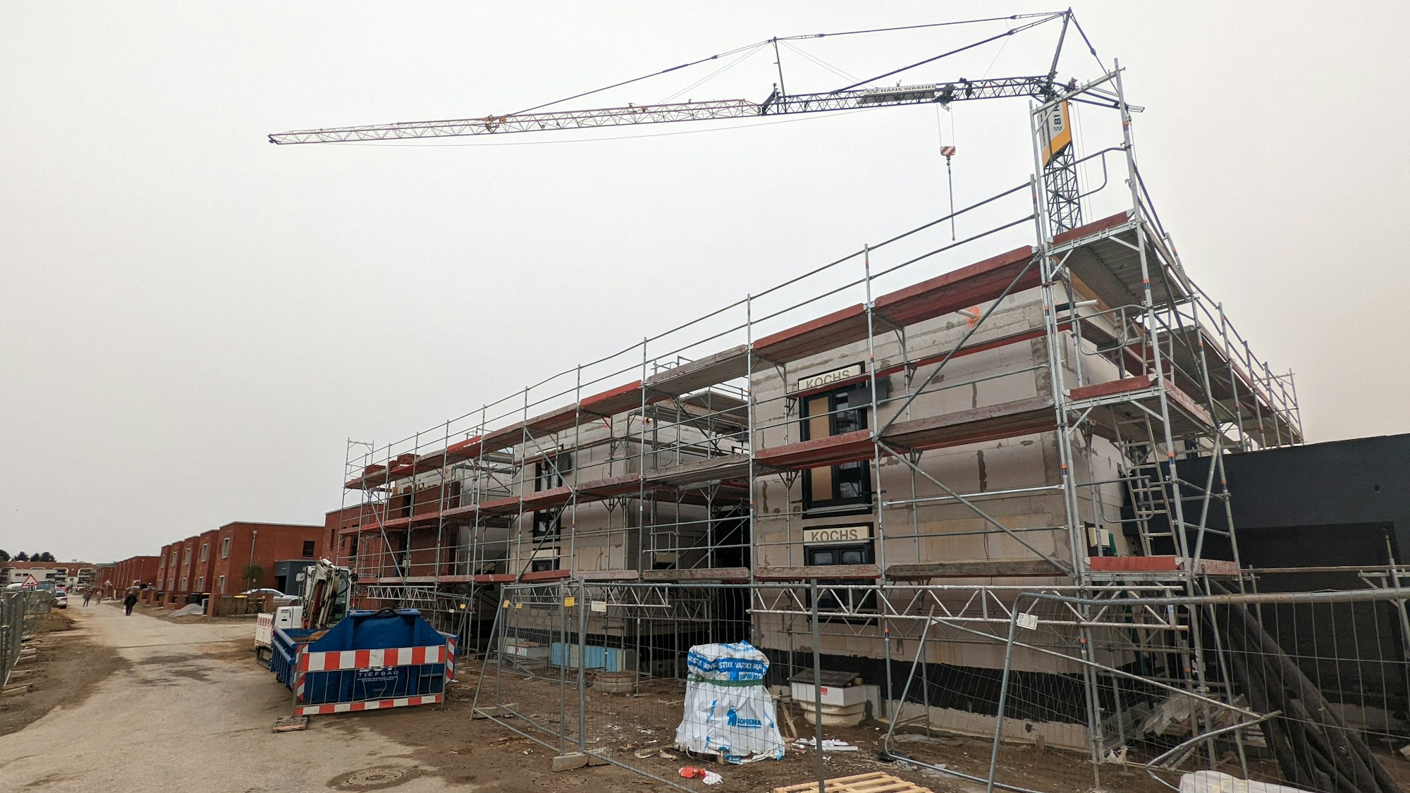 Ein Rohbau ist von Gerüst umrandet, dahinter steht ein Kran.