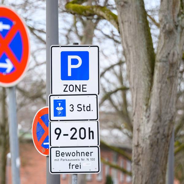 Schilder mit Hinweisen zu einer Bewohnerparkzone und eingeschränktem Halteverbot stehen an einer Straße.