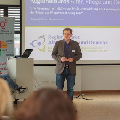 Dietmar Fischer steht vor Publikum und präsentiert.