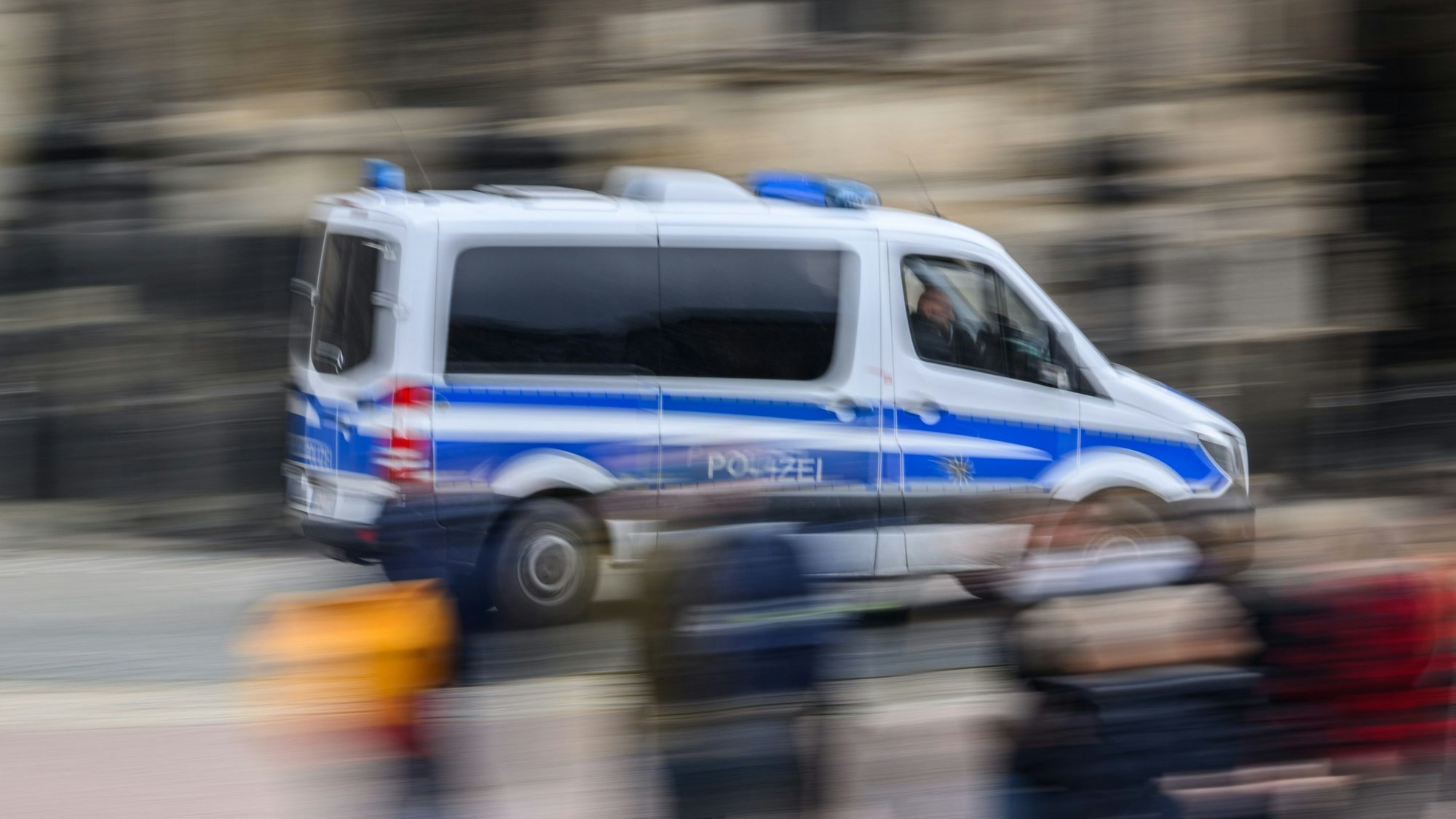 Das Foto zeigt einen blau-weißen Mannschaftswagen der Polizei im Einsatz.