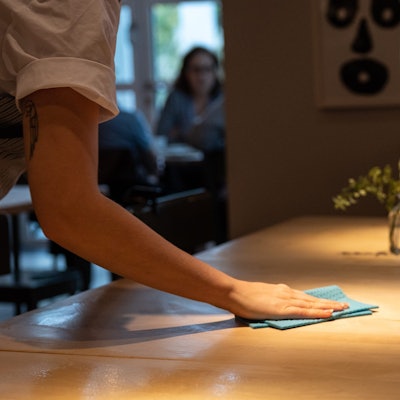 Eine Bedienung wischt einen Tisch im Restaurant sauber